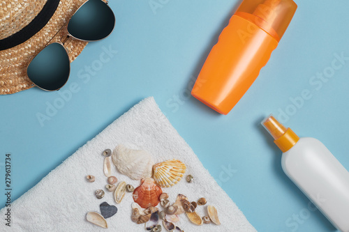 Sun cream, sun hat, cream, sunscreen bottle, sun cream, lotion bottle, sunglasses seashells on a blue background. Sun protection. Beach flat lay accessories. Summer travel holiday concept
