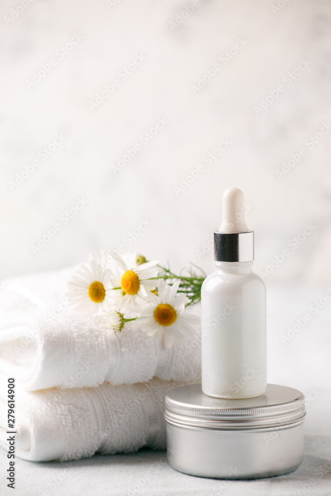 Spa and wellness setting. Composition with chamomile flowers and cosmetic bottle of essential oil serum and cream in zero waste pacage on white background