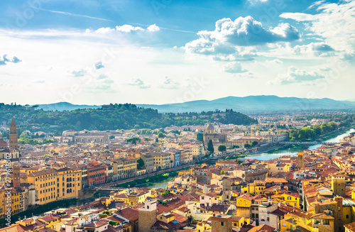 Top aerial panoramic view of Florence city historical centre, bridges over Arno river, buildings houses with orange red tiled roofs, blue sky white clouds background, Tuscany, Italy © Aliaksandr