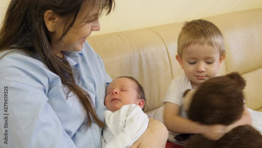 Mother holding newborn baby, toddler brother child holding teddy bear toy Mother holding newborn baby, toddler brother child holding teddy bear toy