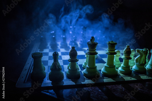 Chess board game concept of business ideas and competition. Chess figures on a dark background with smoke and fog.