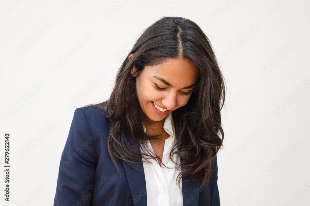 Happy young woman looking down. Portrait of beautiful smiling brunette businesswoman isolated on grey background. Emotion concept Happy young woman looking down. Portrait of beautiful smiling brunette businesswoman isolated on grey background. Emotion concept