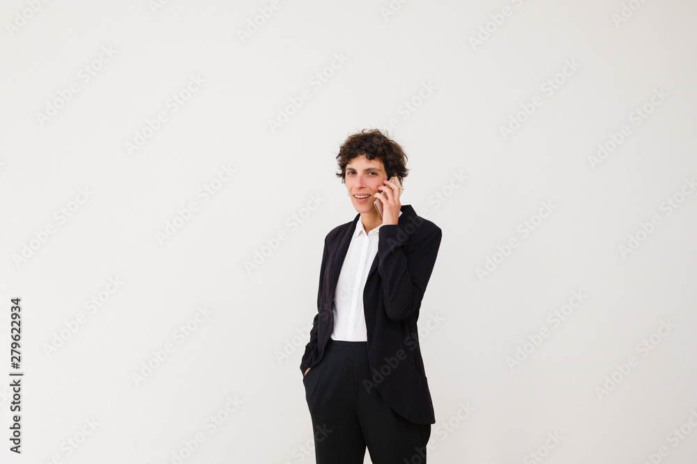Happy businesswoman talking by smartphone. Professional middle aged businesswoman talking by cell phone and smiling at camera isolated on grey background. Communication concept Happy businesswoman talking by smartphone. Professional middle aged businesswoman talking by cell phone and smiling at camera isolated on grey background. Communication concept