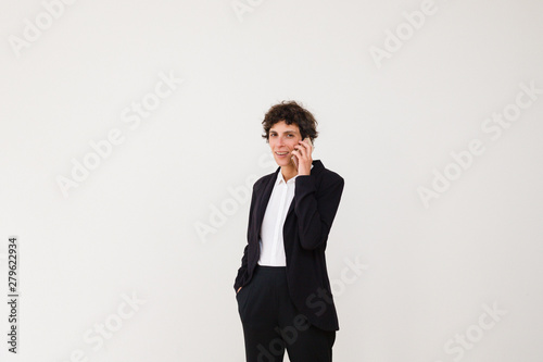 Happy businesswoman talking by smartphone. Professional middle aged businesswoman talking by cell phone and smiling at camera isolated on grey background. Communication concept