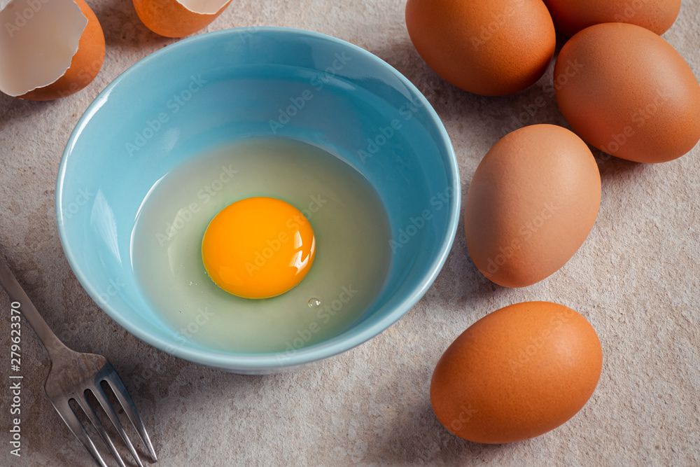 Raw broken egg with yolk in bowl . Raw broken egg with yolk in bowl .