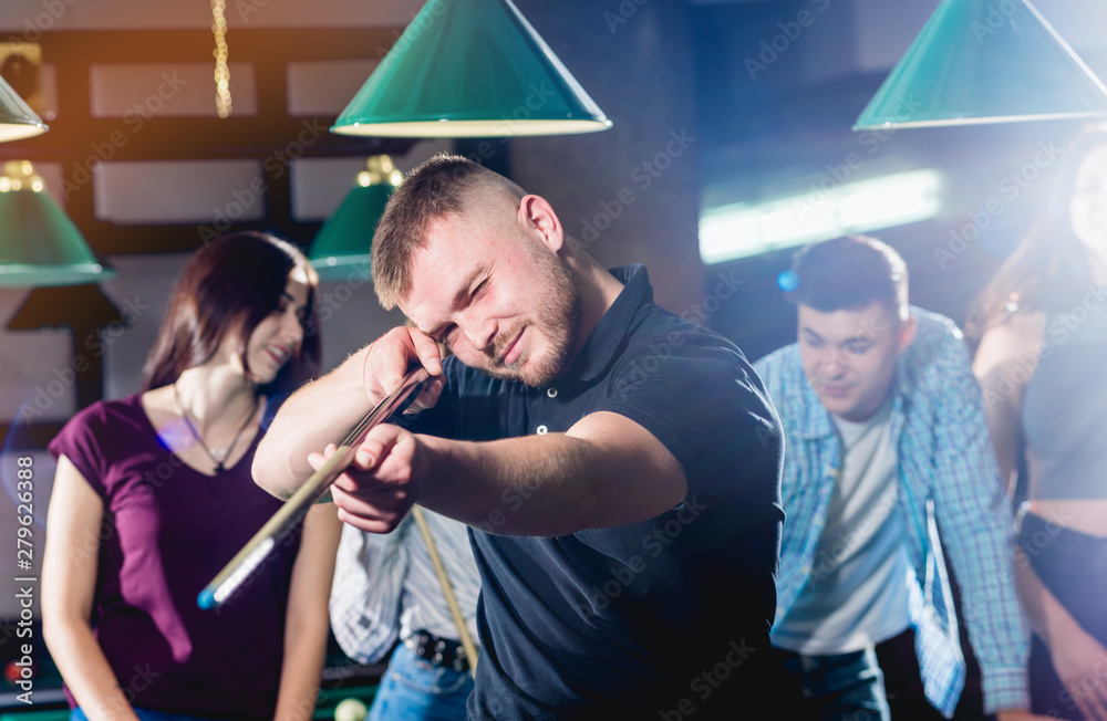 Fototapeta premium Young man playing in billiard. Posing near the table with a cue in his hands