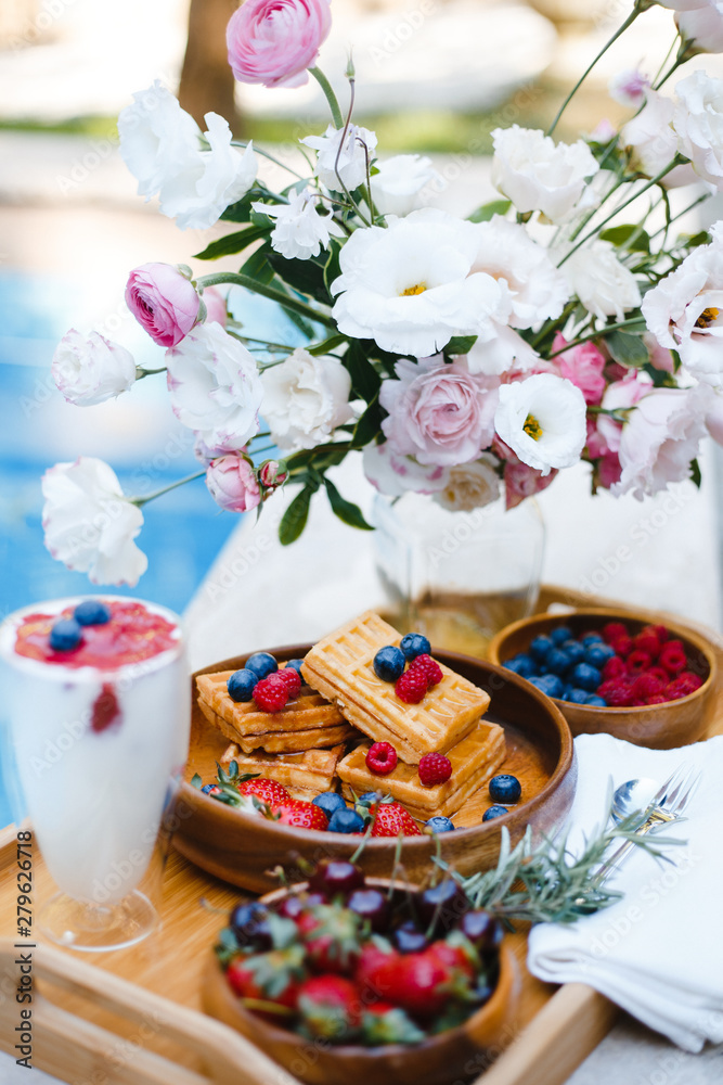 breakfast by the pool with fruits and berries in wooden bowls: waffles, milkshake, strawberries, raspberries, blueberries, cherries, orange slices, lemon, lime, watermelon and pineapple breakfast by the pool with fruits and berries in wooden bowls: waffles, milkshake, strawberries, raspberries, blueberries, cherries, orange slices, lemon, lime, watermelon and pineapple