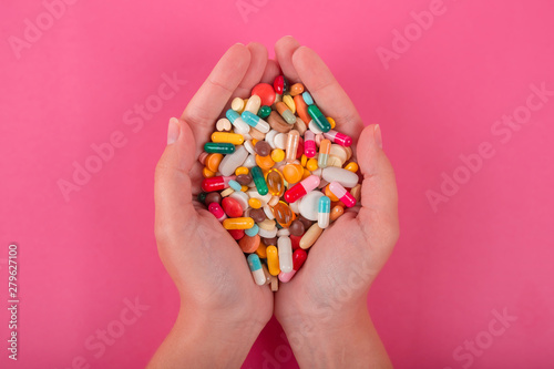 Colorful pills and medicines in the hand on pink background