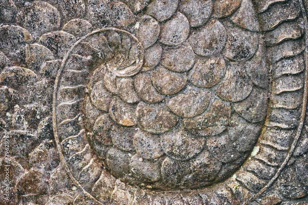 Texture of dragon carved out from stone with highly detailed scales. Ubud, Bali, Indonesia.