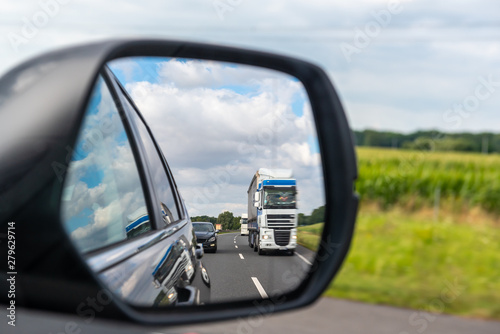 Asphalt road with truck reflected in car mirror. © vivoo