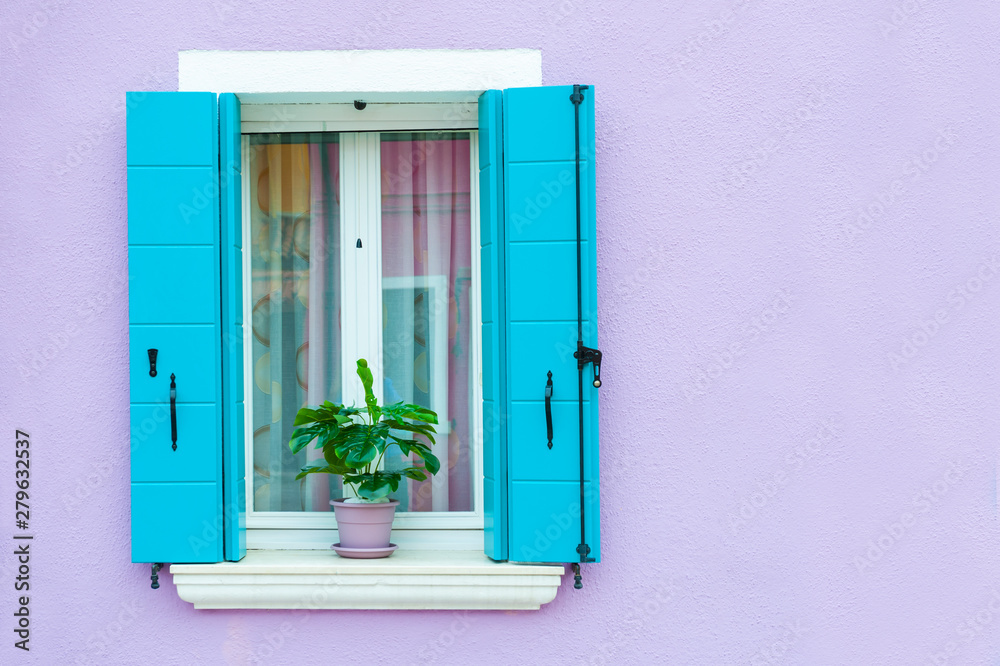 Window with blue shutters on the violet wall. Colorful architecture in Burano island, Venice, Italy.