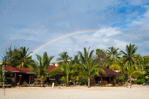Scenery tropical coast with palm trees and double rainbow in the sky