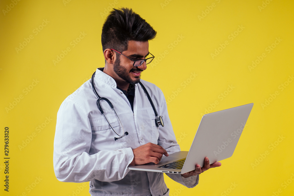 Portrait of indian male doctor checking medicine in yellow studio background Portrait of indian male doctor checking medicine in yellow studio background
