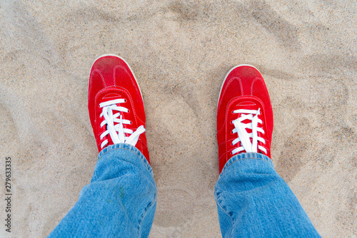 Red sneakers with white laces. Blue jeans.