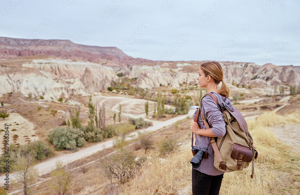 Naklejka premium Travel concept. Travelling young woman with backpack enjoying mountains view.
