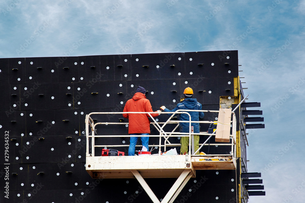 External facade thermal insulation. Professional construction workers on  scissor lift insulating wall facade with mineral wool for thermal  protection. Workers wearing safety harness insulated wall Photos | Adobe  Stock
