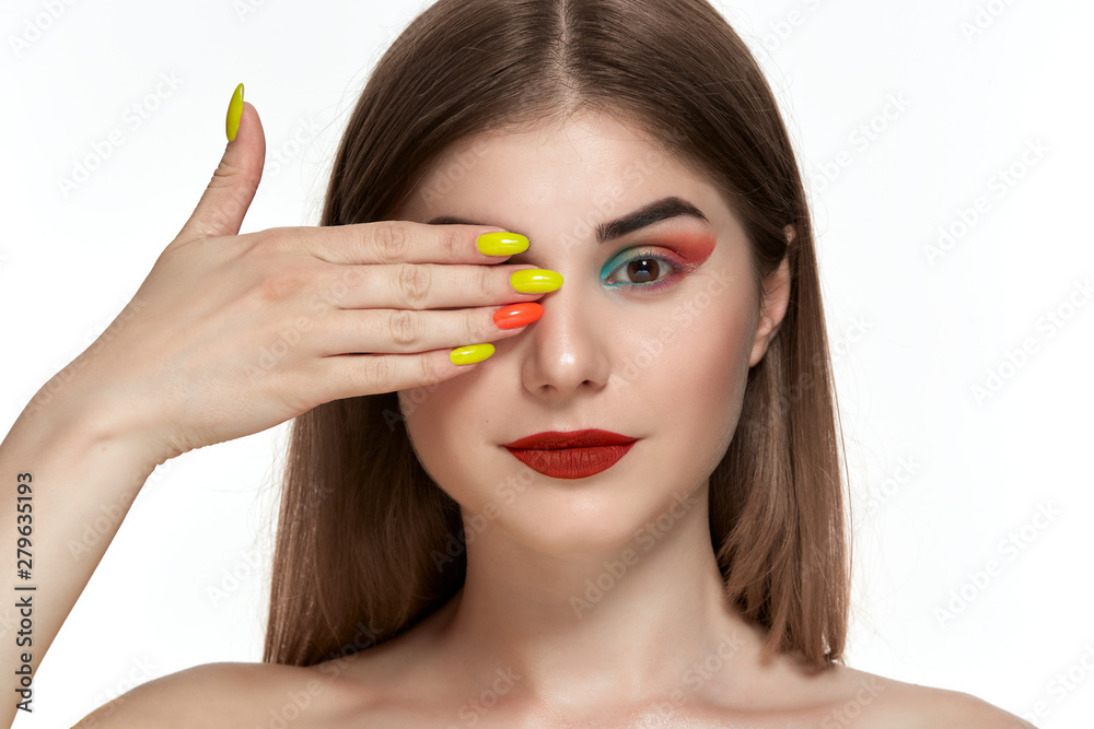 Closeup portrait of beautiful young woman with bright color make-up holding hands with bright  manicure close to face