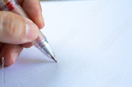 Woman s left Hand holding a plastic pen  writing letter on white paper background  Notebook  Close up   Macro shot  Selective focus  Communication  Stationery concept