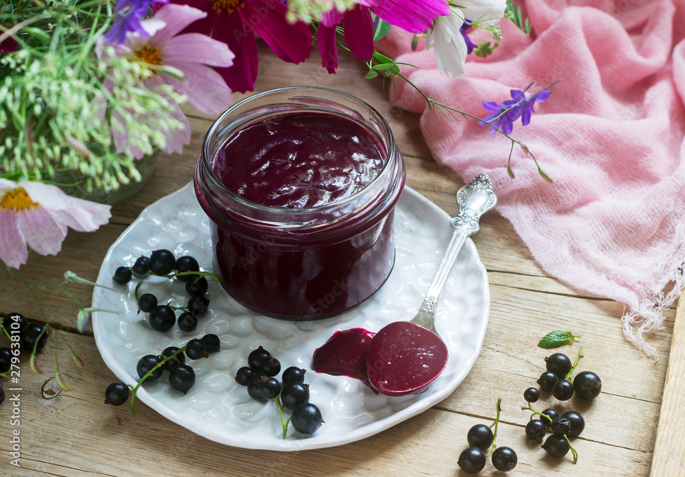Black currant custard, currants and a bouquet of wild flowers on a wooden background. Rustic style. Black currant custard, currants and a bouquet of wild flowers on a wooden background. Rustic style.
