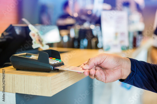 Hand put credit card In slot of credit card reader with blurry cashier at counter service, credit card payment, buy and sell products & service, the concept of payment without cash, selective focus.