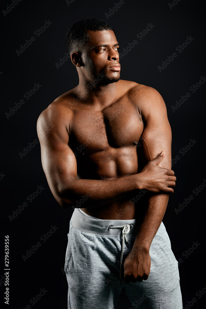 sexy thoughtful pensive well-built athlete keeping his arm, looking away, aside, posing to the camera. close up portrait, isolated black background. studio shot