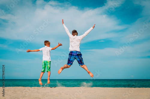 father and son have fun jump at tropical beach