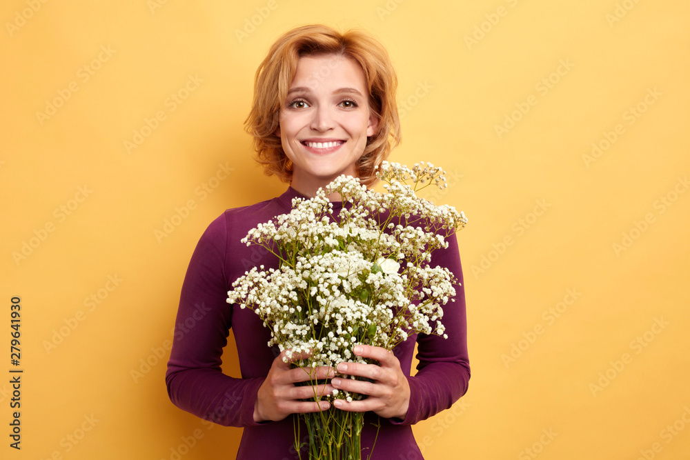pretty attractive charming lady with blond hair , holding a bunch of wild flowers. close up portrait isolated yellow background. studio shot. happiness. gift from boyfriend pretty attractive charming lady with blond hair , holding a bunch of wild flowers. close up portrait isolated yellow background. studio shot. happiness. gift from boyfriend