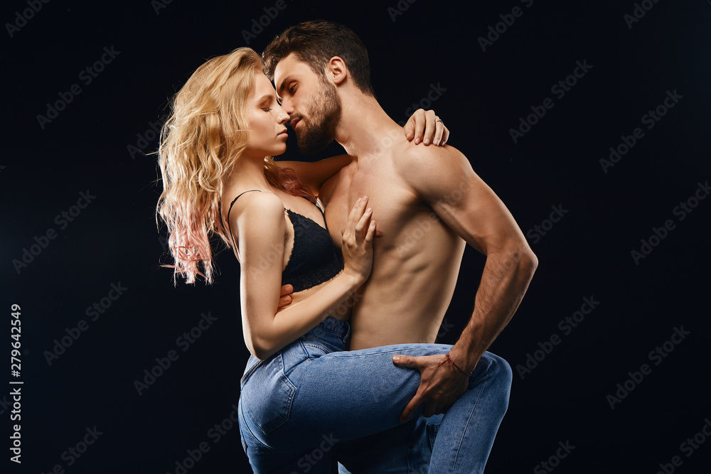 shirtless man and blonde woman dancing tango in the studio, performance,isolated black background.