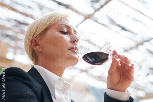 Serious winery expert holding bokal of red wine evaluating its smell photo