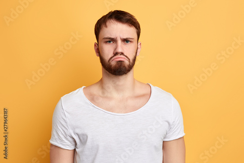 serious sad man expresses sad expression , crooked lower lip with a disgruntled look.man has heard bad news, information.guy is dissapointed by bad results of exams. close up portrait