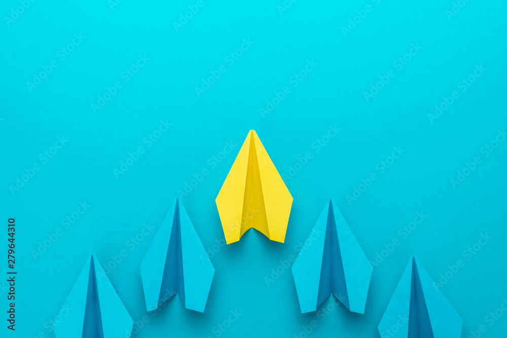 Top view of yellow plane leading blue ones. Leadership concept with paper planes over turquoise blue background with copy space. Flat lay image of business competition concept. Top view of yellow plane leading blue ones. Leadership concept with paper planes over turquoise blue background with copy space. Flat lay image of business competition concept.