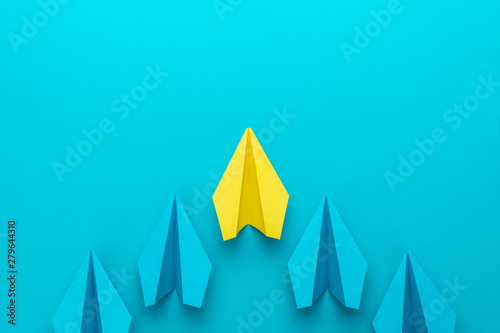 Top view of yellow plane leading blue ones. Leadership concept with paper planes over turquoise blue background with copy space. Flat lay image of business competition concept.