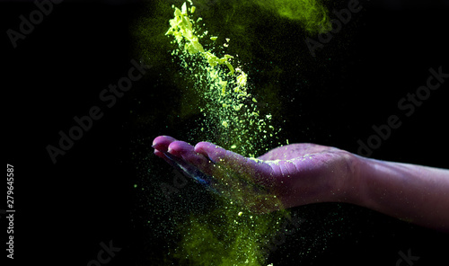 Yellow holi powder follow down through woman hand on black