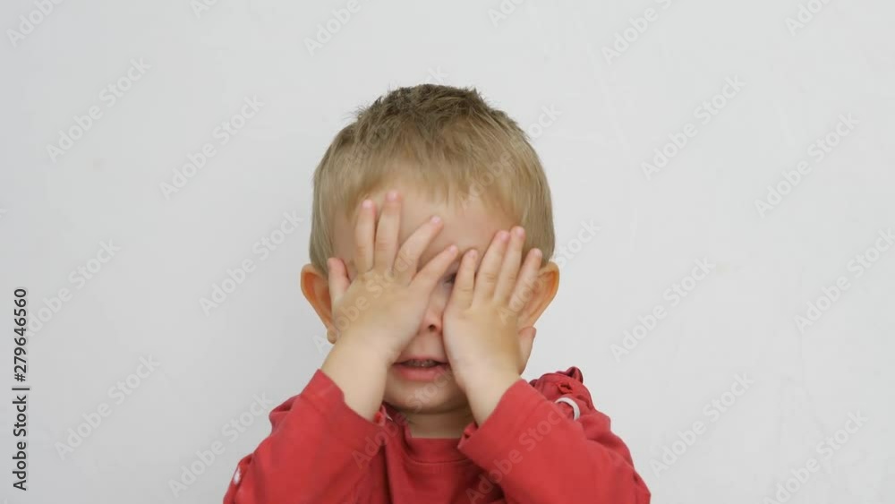 Funny blond child covering his blue eyes with little hands, playful kid Funny blond child covering his blue eyes with little hands, playful kid