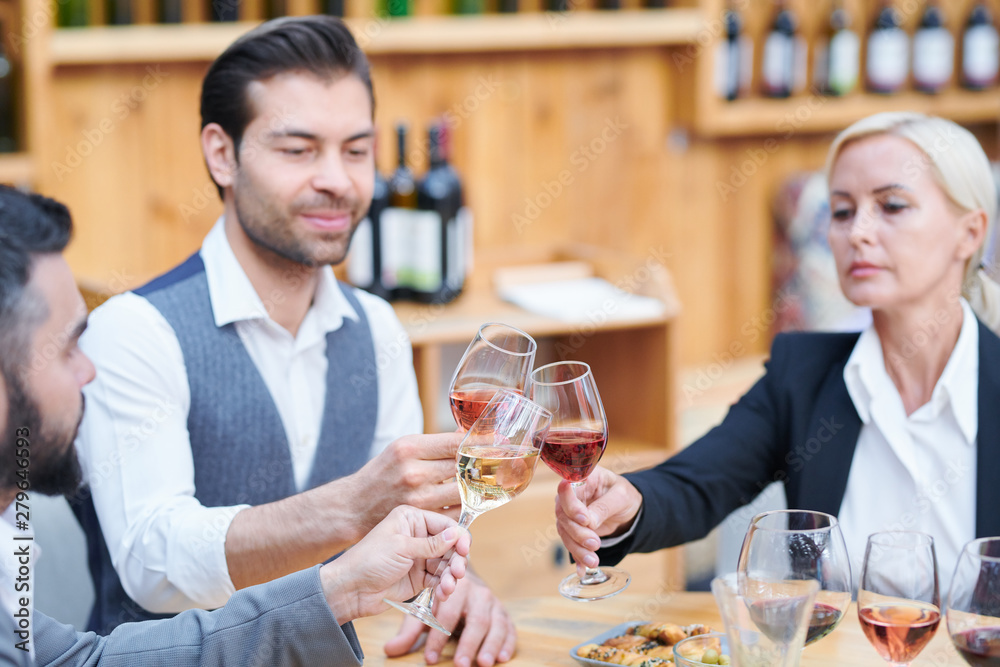 Group of contemporary winery experts clinking with glasses of various wine Group of contemporary winery experts clinking with glasses of various wine