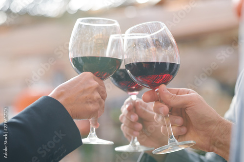 Hands of friends or business partners clinking with wineglasses with red wine photo