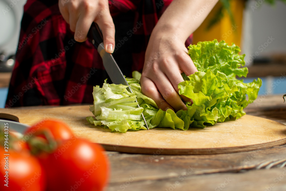 hands of the girl cut lettuce on a table, a woman prepares a veggie salad, healthy food, a knife chops greens hands of the girl cut lettuce on a table, a woman prepares a veggie salad, healthy food, a knife chops greens