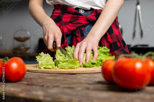 hands of the girl cut lettuce on a table, a woman prepares a veggie salad, healthy food, a knife chops greens