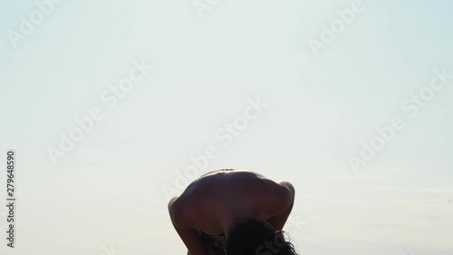 Hot sexy brunette woman trying to dry her wet hair while turning her head on the beach in slow motion photo