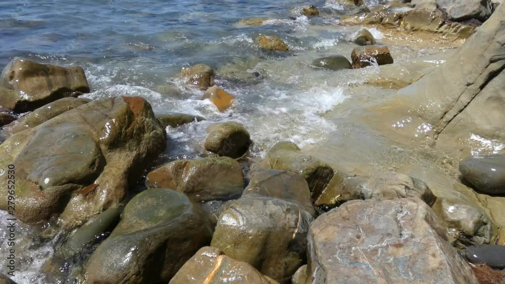 Sea surf on big rocks. Water waves on beach with multicolored polished stones, closeup view. Sunny summer day. With original sound. Natural background. Sea surf on big rocks. Water waves on beach with multicolored polished stones, closeup view. Sunny summer day. With original sound. Natural background.