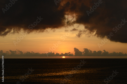 水平線に沈む夕日と穏やかな海岸 © Ta-c