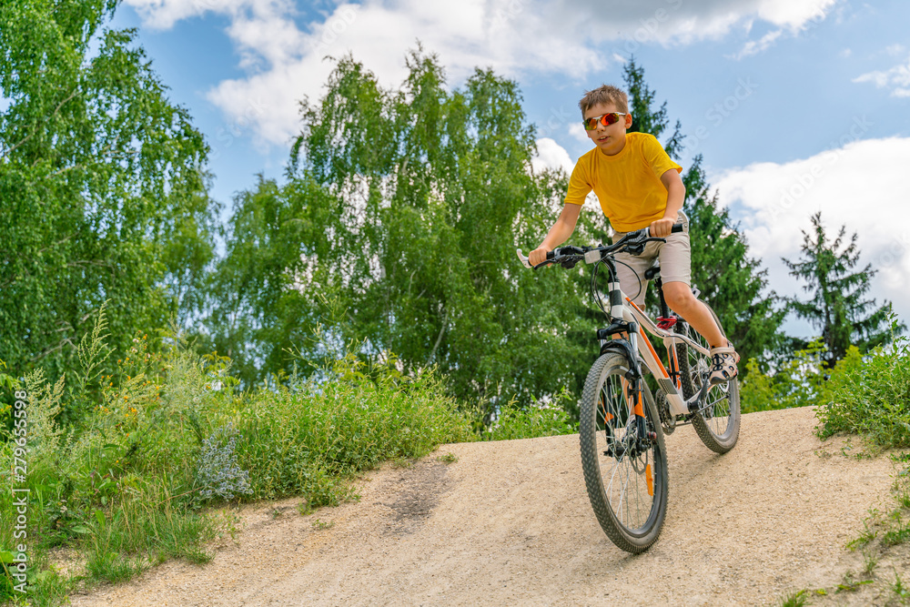 A boy on a bike down the hill on a forest road