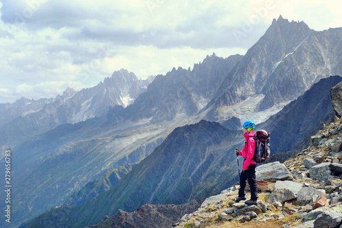 Woman Hiker with backpacks relaxing on top of a mountain and enjoying the view of valley
