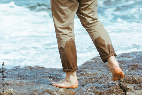 wet man legs in pants walking by sea rocky beach enjoying water © phpetrunina14