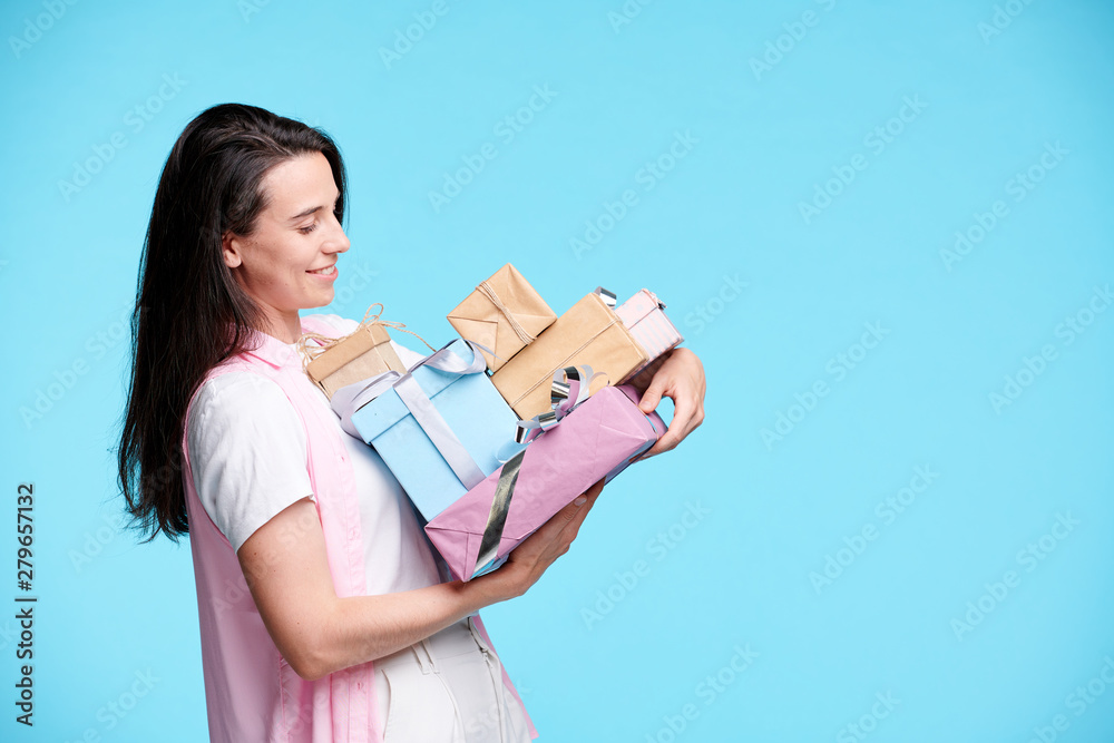 Happy young woman looking at pile of giftboxes in her hands Happy young woman looking at pile of giftboxes in her hands