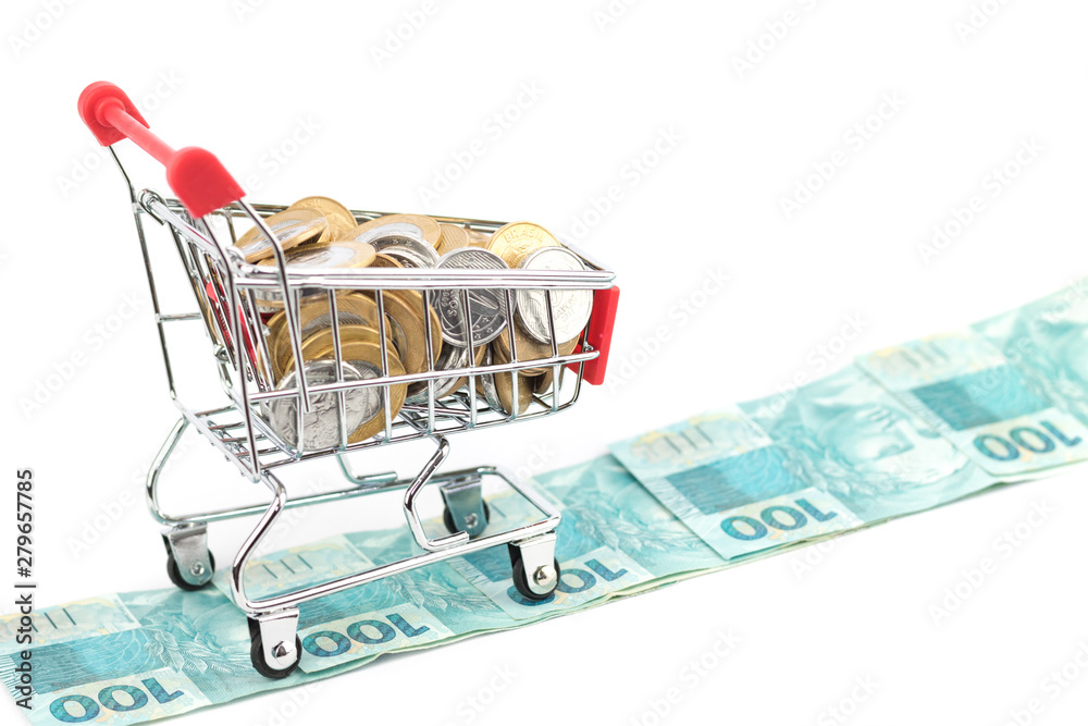 Shopping cart or supermarket cart full of Brazilian coins in the way of one hundred real notes, concept of shopping for business finance. Money from Brazil.