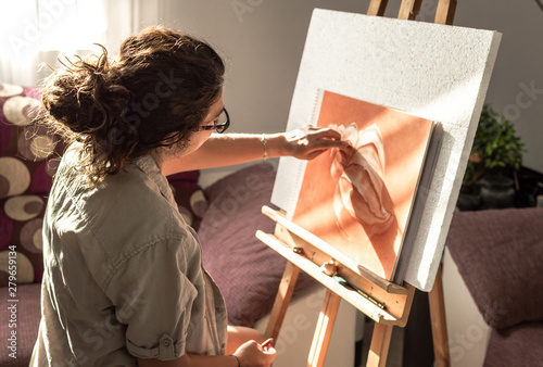 Schilderij op canvas Woman with casual clothes and glasses painting with sanguine or red chalk