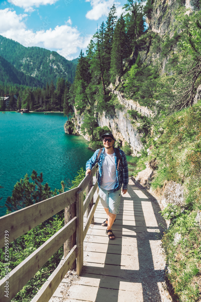 Naklejka premium man walking by hiking trail around braies lake in italy dolomites mountains