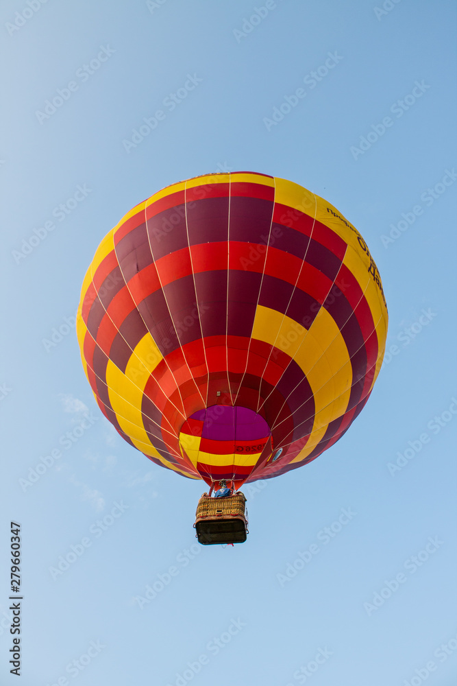 Naklejka premium flying balloon with passengers in a basket against the blue sky at the festival of Aeronautics in Pereslavl-Zalessky Russia summer evening