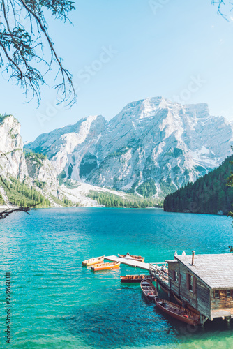 view of wooden house on water with pier and boats lake in dolomites mountains